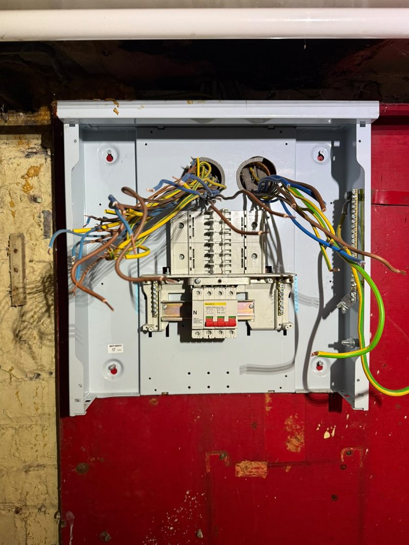 A three-phase distribution board part way through installation, chassis exposed and the circuit conductors drawn in ready to terminate.